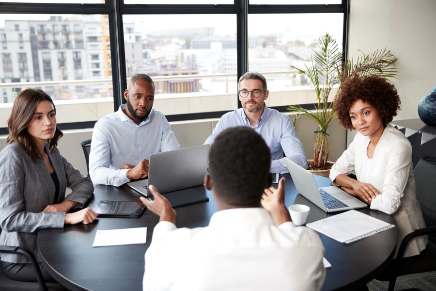 Four people actively listening to the speaker in a meeting at a round table.